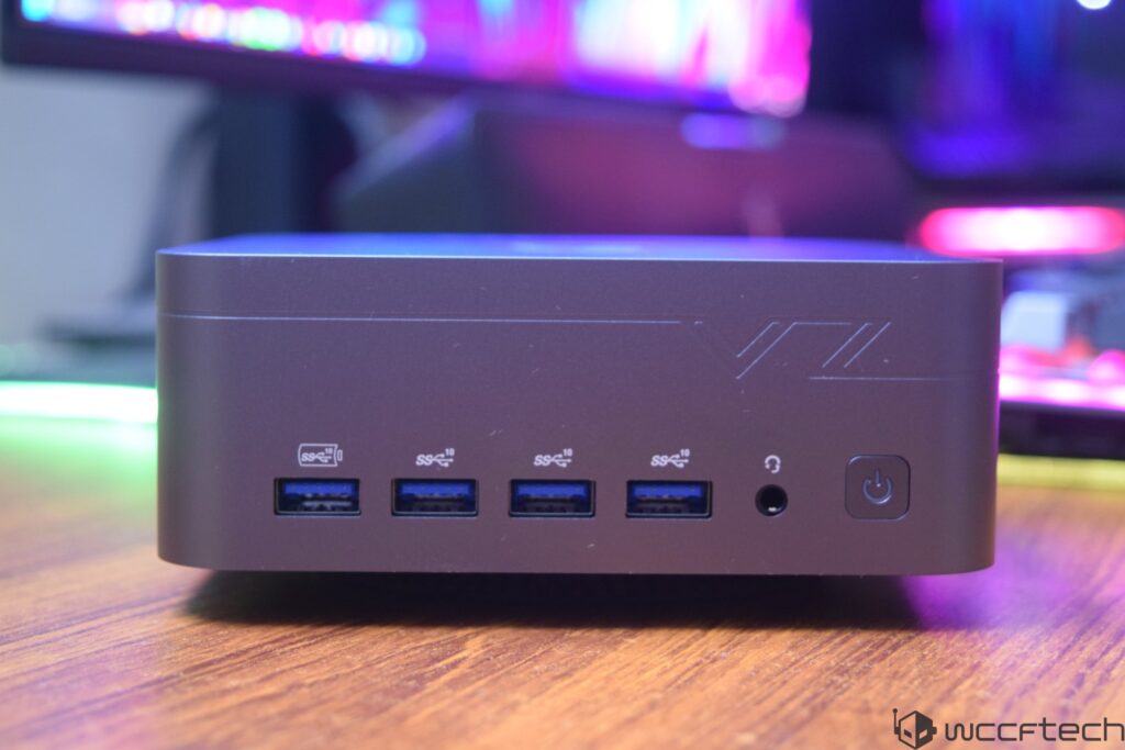 A device with four USB ports labeled 'SS 10' and a headphone jack on the front, placed on a wooden surface with colorful ligh