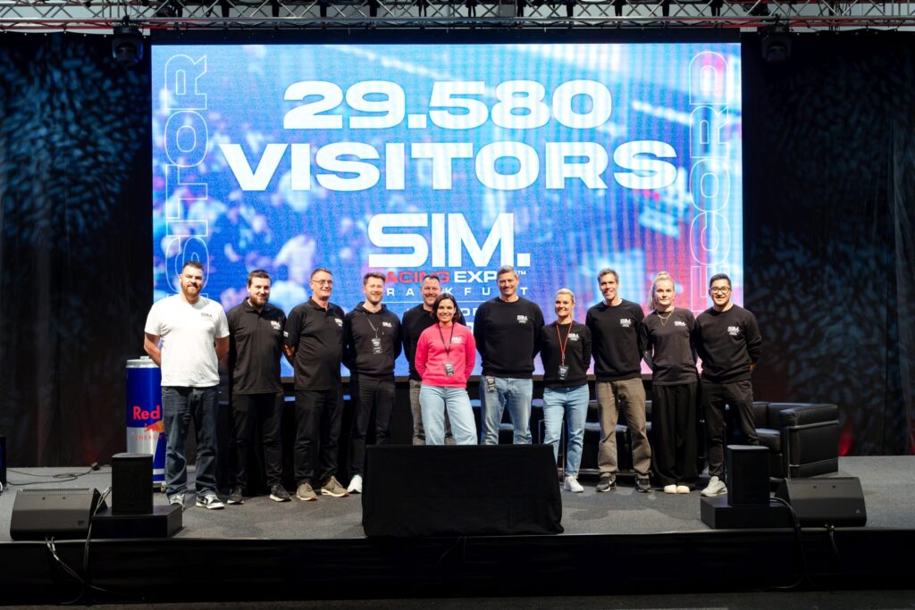 A group of people stands on stage in front of a screen displaying '29,580 Visitors SIM Racing Expo' at the Frankfurt esports 