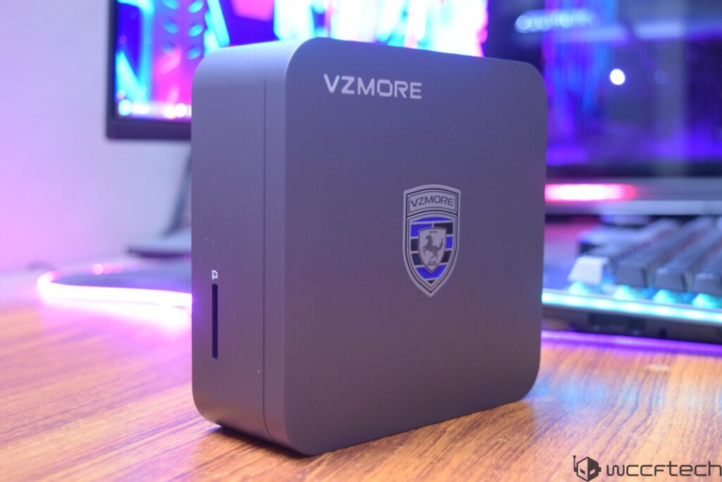 A VZMORE device is placed on a desk in front of a monitor with colorful lighting.