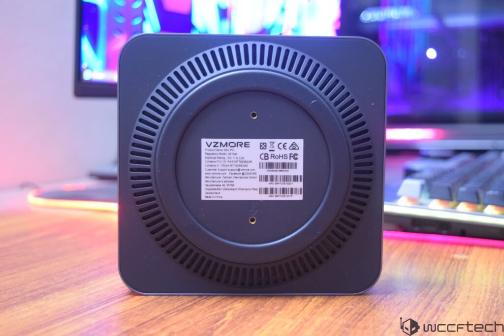 A VZMORE Mini PC is shown from the back, displaying a label with specifications and regulatory compliance information.